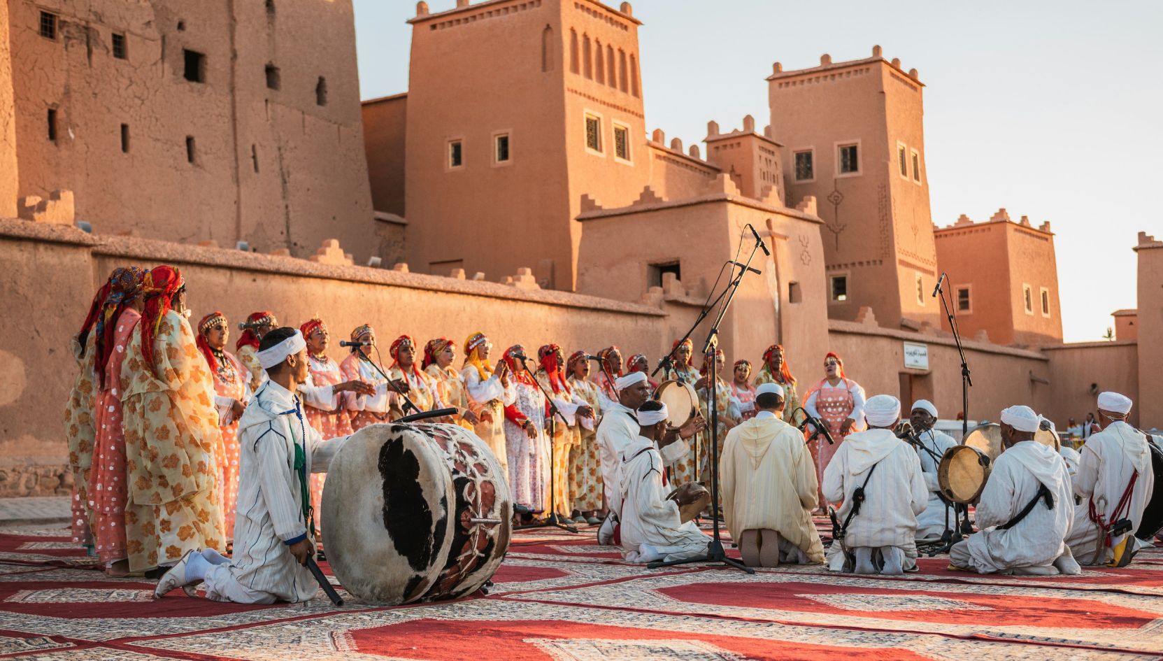 Traditional Berber musicians and dancers performing in front of the Taourirt Kasbah in Ouarzazate, Morocco, during a cultural festival.