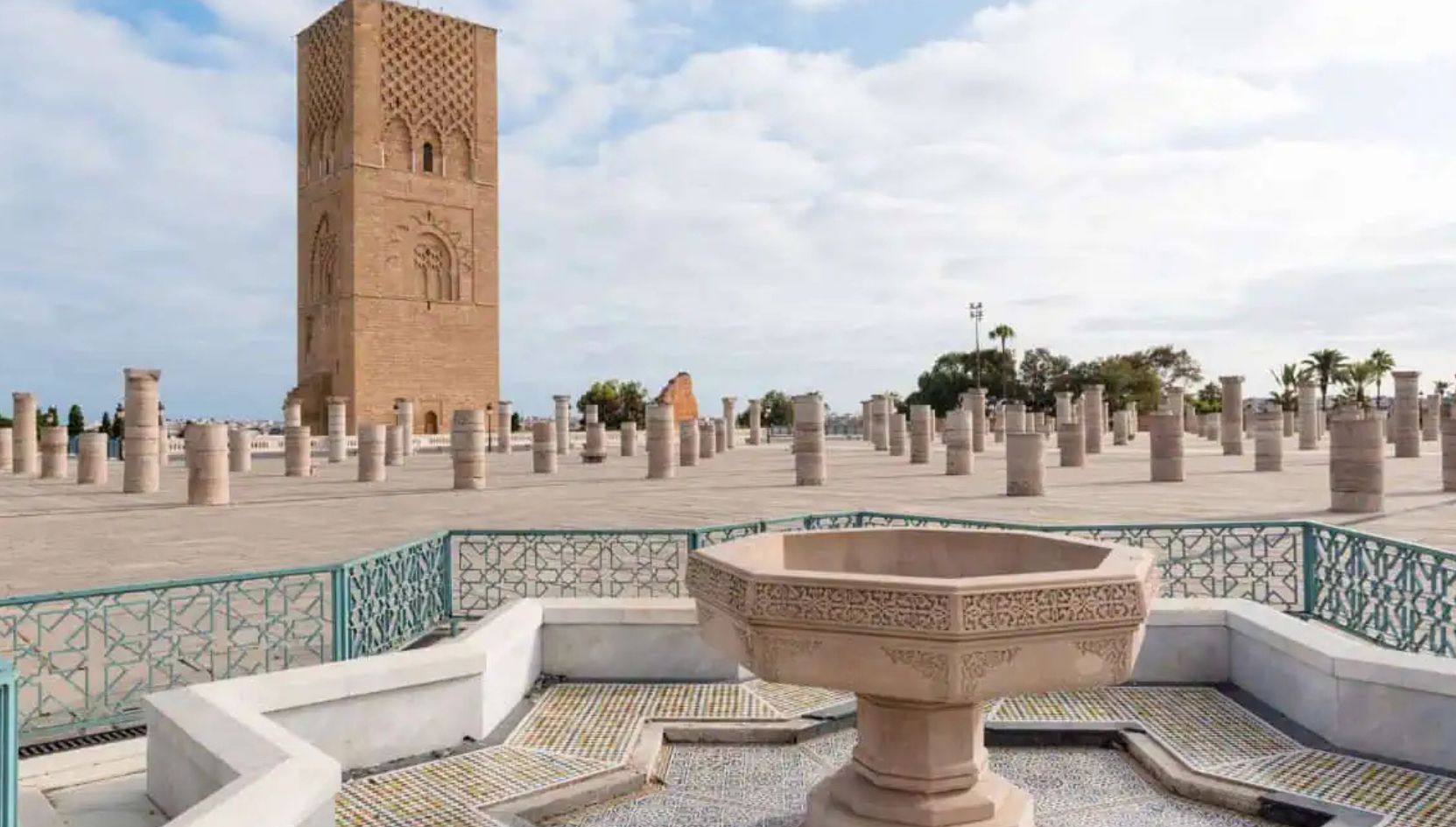 Hassan Tower and the esplanade of stone columns in Rabat, Morocco, with a traditional fountain in the foreground.