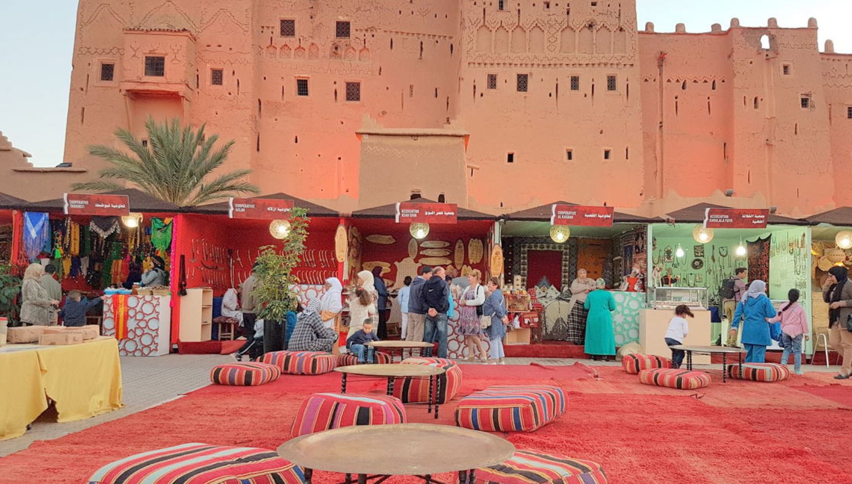 Traditional market in front of Kasbah Taourirt in Ouarzazate, Morocco, with colorful Berber crafts and local artisans.