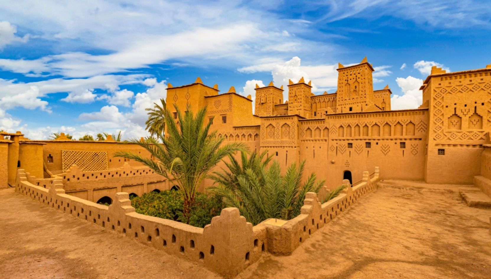 Kasbah Taourirt in Ouarzazate, Morocco, showing traditional Berber earthen architecture under a bright blue sky.