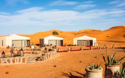 Luxury desert camp with white tents in the golden dunes of Erg Chebbi, Merzouga, Morocco.