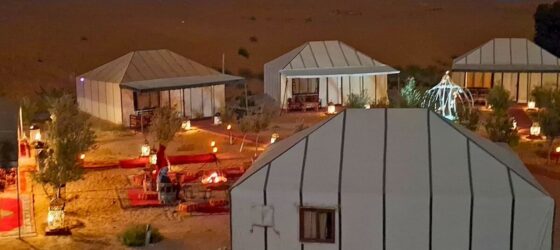 Night ambiance at Merzouga Luxury Desert Camp with glowing lanterns, tents, and cozy seating areas in the Sahara.