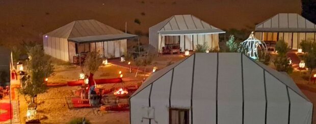 Night ambiance at Merzouga Luxury Desert Camp with glowing lanterns, tents, and cozy seating areas in the Sahara.