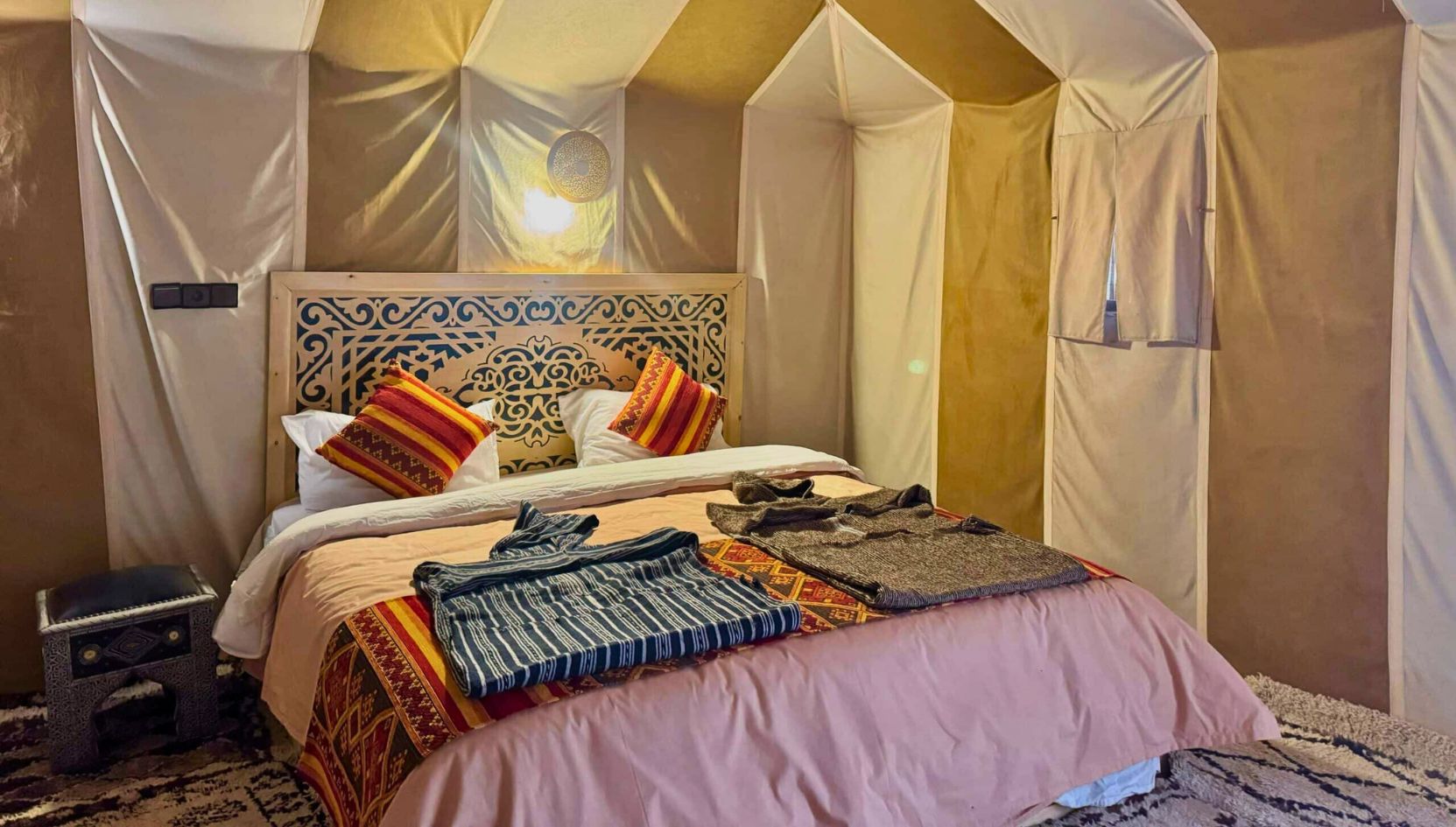 Luxury desert camp bedroom in Merzouga with traditional Moroccan decor and comfortable double bed.