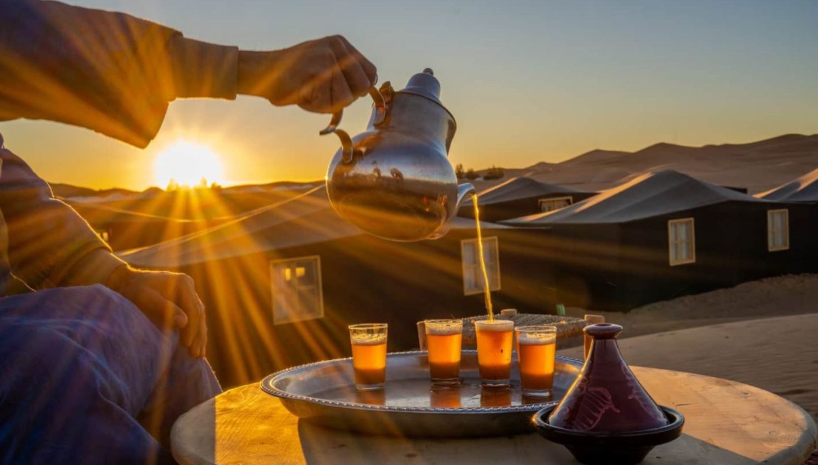 Traditional Moroccan mint tea being poured at sunset in a Berber desert camp in Zagora, Morocco.