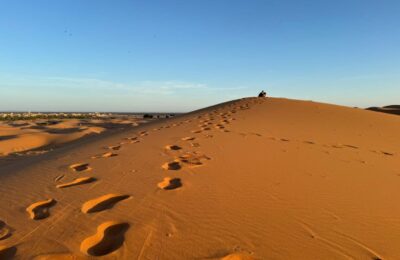 Footprints leading up a golden sand dune at sunrise in the Erg Chebbi desert near Merzouga, Morocco