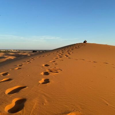 Footprints leading up a golden sand dune at sunrise in the Erg Chebbi desert near Merzouga, Morocco