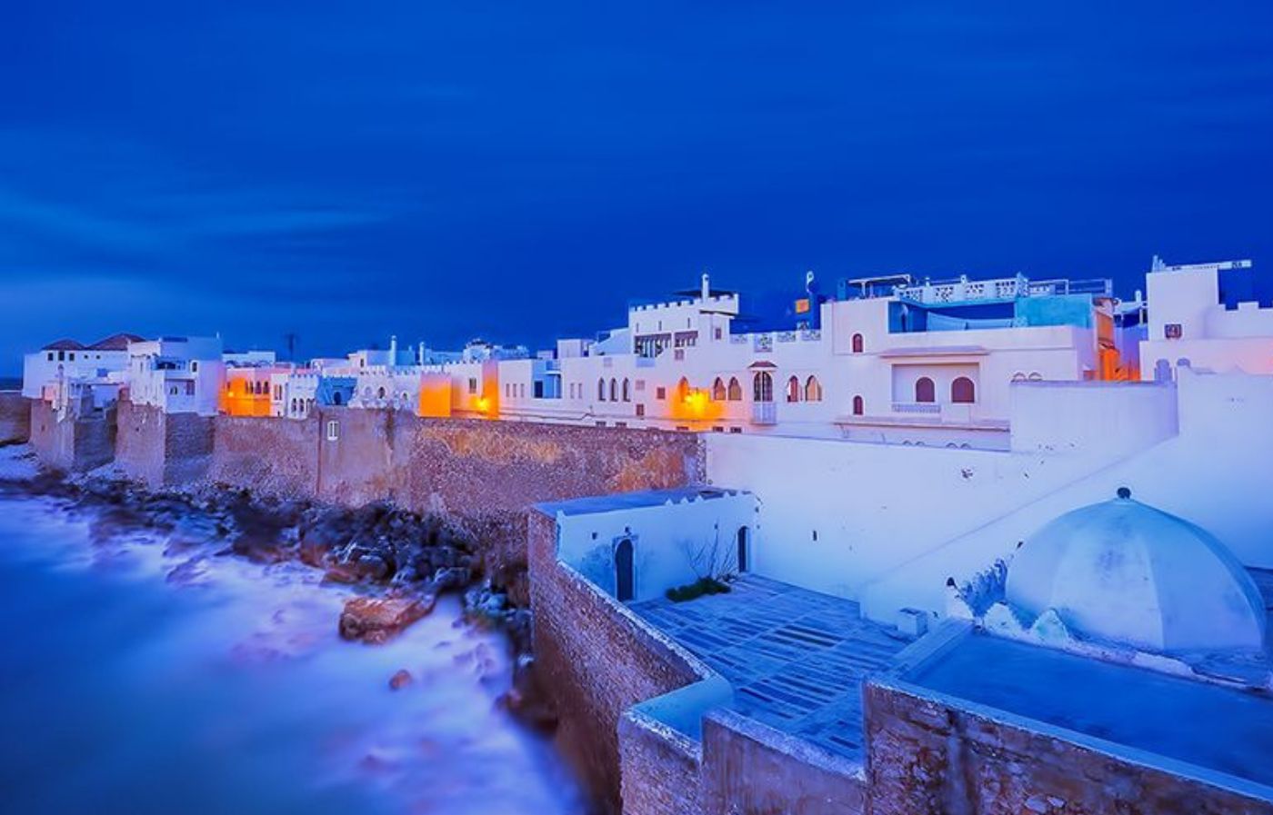Night view of Asilah Medina with whitewashed houses and illuminated seaside walls overlooking the Atlantic Ocean