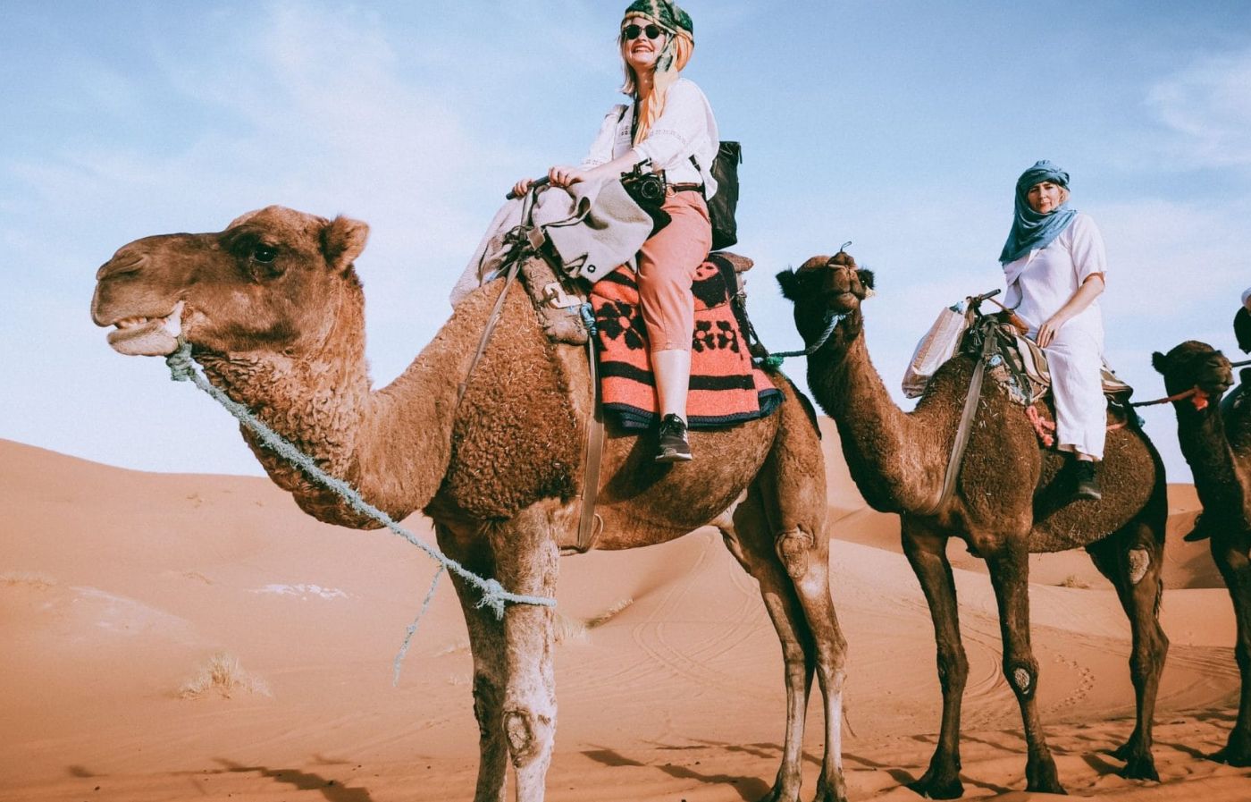 Tourists riding camels in the Sahara Desert during a Merzouga camel trek experience