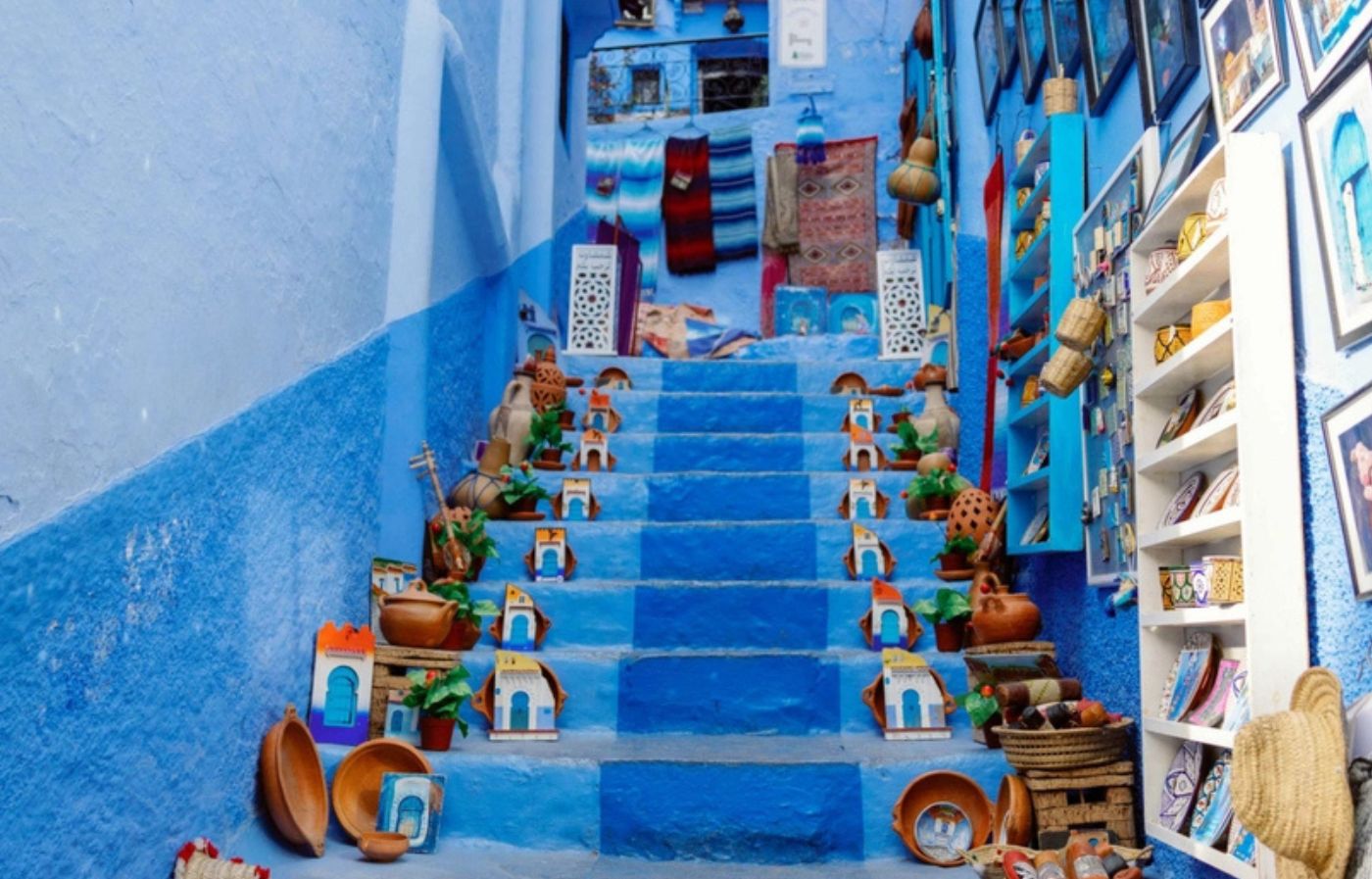 Colorful Moroccan crafts and pottery displayed on the blue-painted stairs of Chefchaouen Medina in northern Morocco