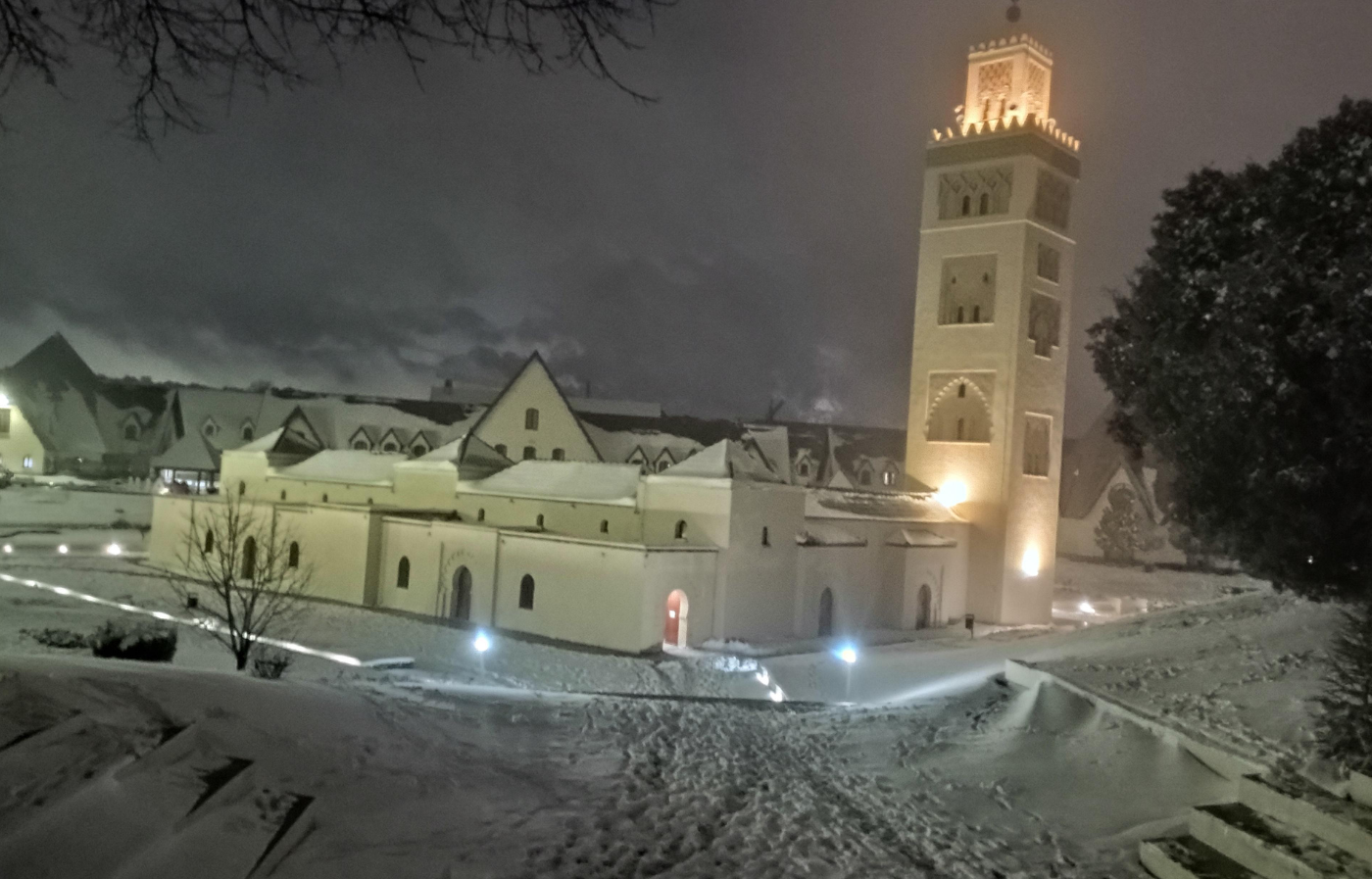 Grand Mosque of Ifrane covered in snow at night with illuminated minaret in the Middle Atlas, Morocco