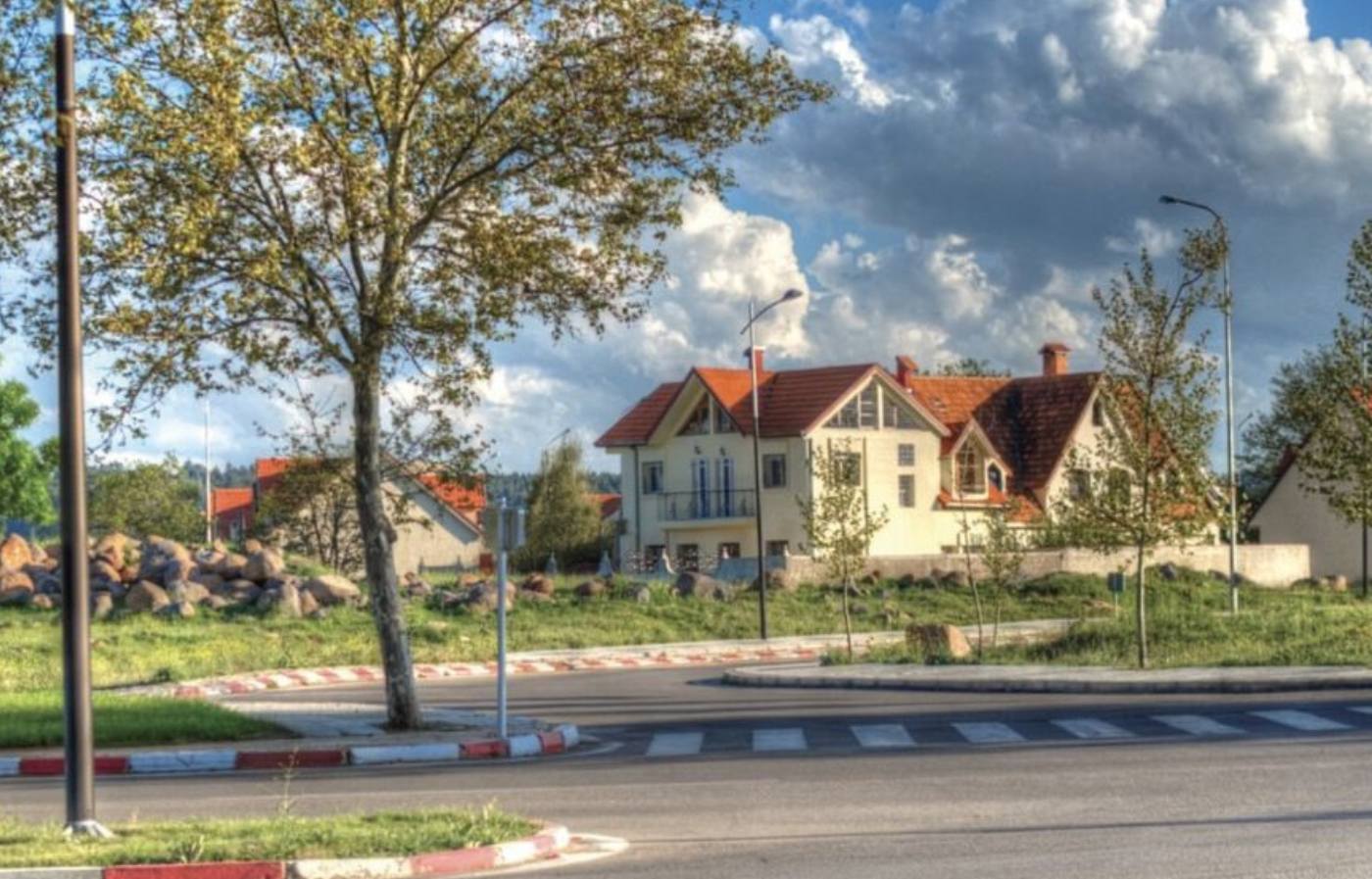 Traditional houses with red roofs in Ifrane surrounded by trees and a roundabout in the Azrou–Midelt region of Morocco