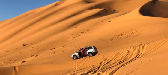 4x4 vehicle driving through the golden sand dunes of Merzouga in the Erg Chebbi desert