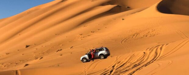 4x4 vehicle driving through the golden sand dunes of Merzouga in the Erg Chebbi desert
