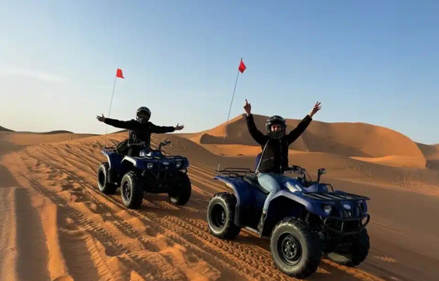 Two people riding quad bikes on the sand dunes of Merzouga in the Sahara Desert