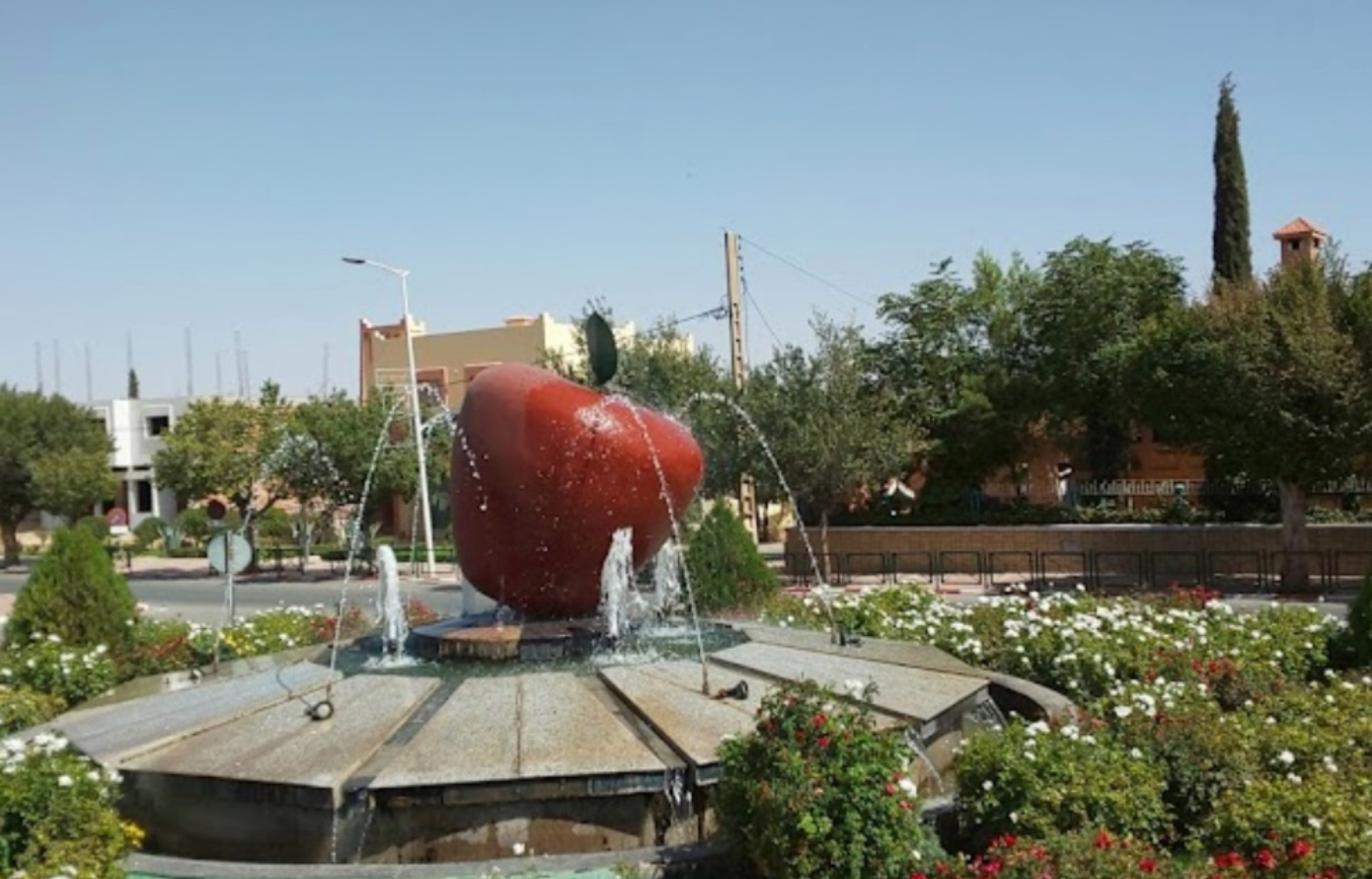 Apple fountain monument in Midelt, Morocco surrounded by flowers and trees